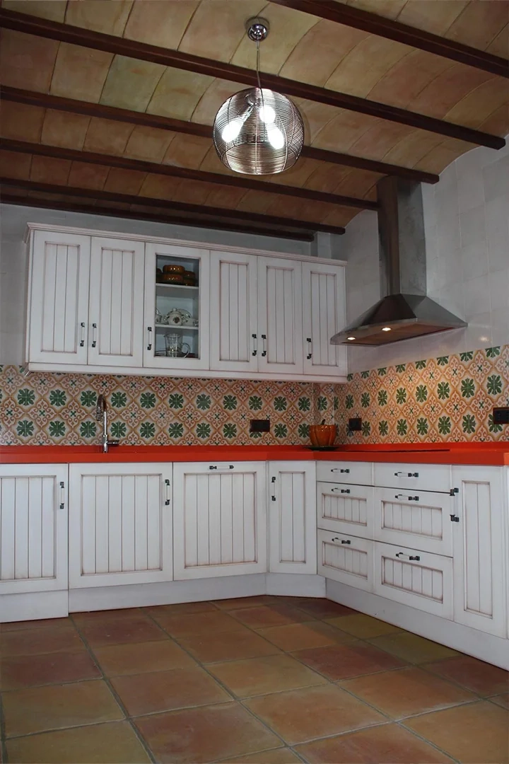 COMPARATIVA-imagen-2 Cocina rústica con azulejos para cocina en pared de inspiración hidráulica, muebles blancos y suelo cerámico en tonos tierra.