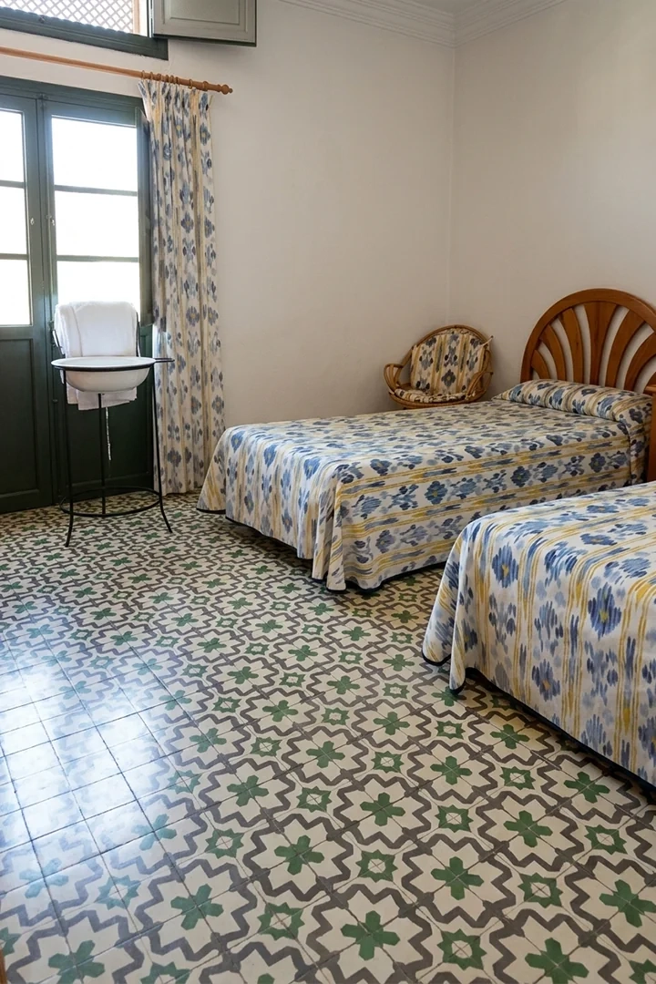 Detalle de un dormitorio con suelo de baldosas para interior estampadas en tonos verdes, grises y blancos.
