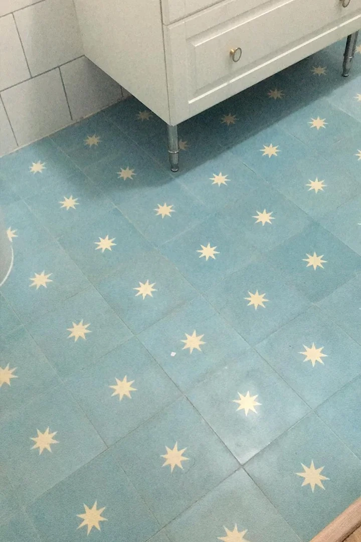 Baño con baldosas para suelo de baño en color azul celeste decoradas con un motivo de estrellas blancas. Un diseño hidráulico que aporta luminosidad, personalidad y un estilo fresco, ideal para baños contemporáneos.