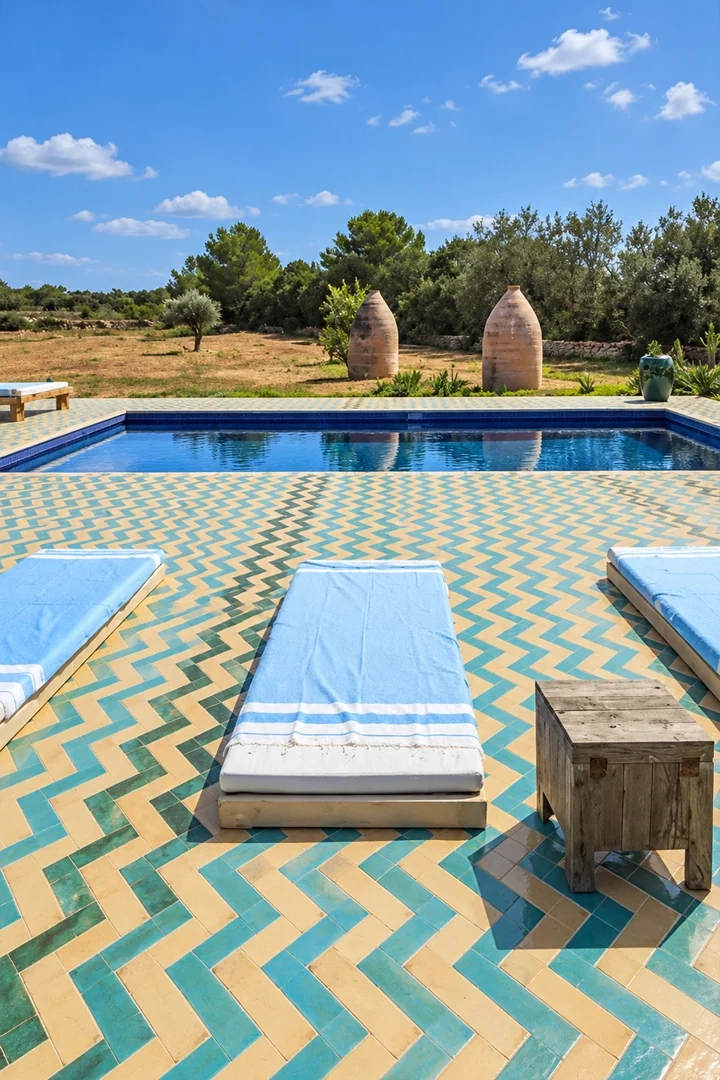 Terraza de piscina con baldosas rectangulares azules y arena colocadas en espiga.